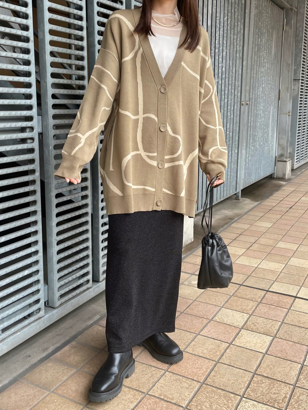 ベージュ系のカーディガン/ボレロ、ブラック系のスカート、ブラック系のブーツを着用したレディースの秋コーディネートの3枚目の写真