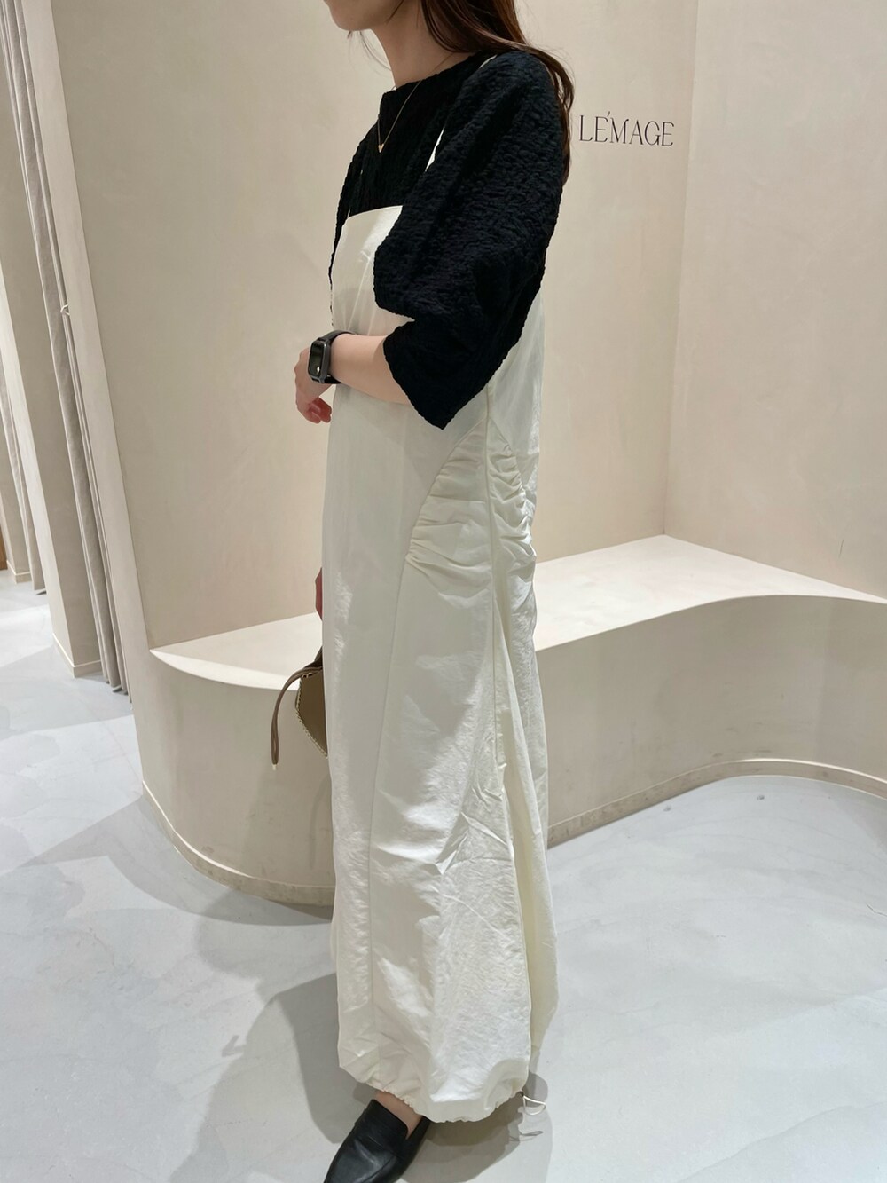 ホワイト系のワンピース、ブラック系のTシャツ/カットソー、ブラウン系のトートバッグを着用したレディースの春コーディネートの2枚目の写真