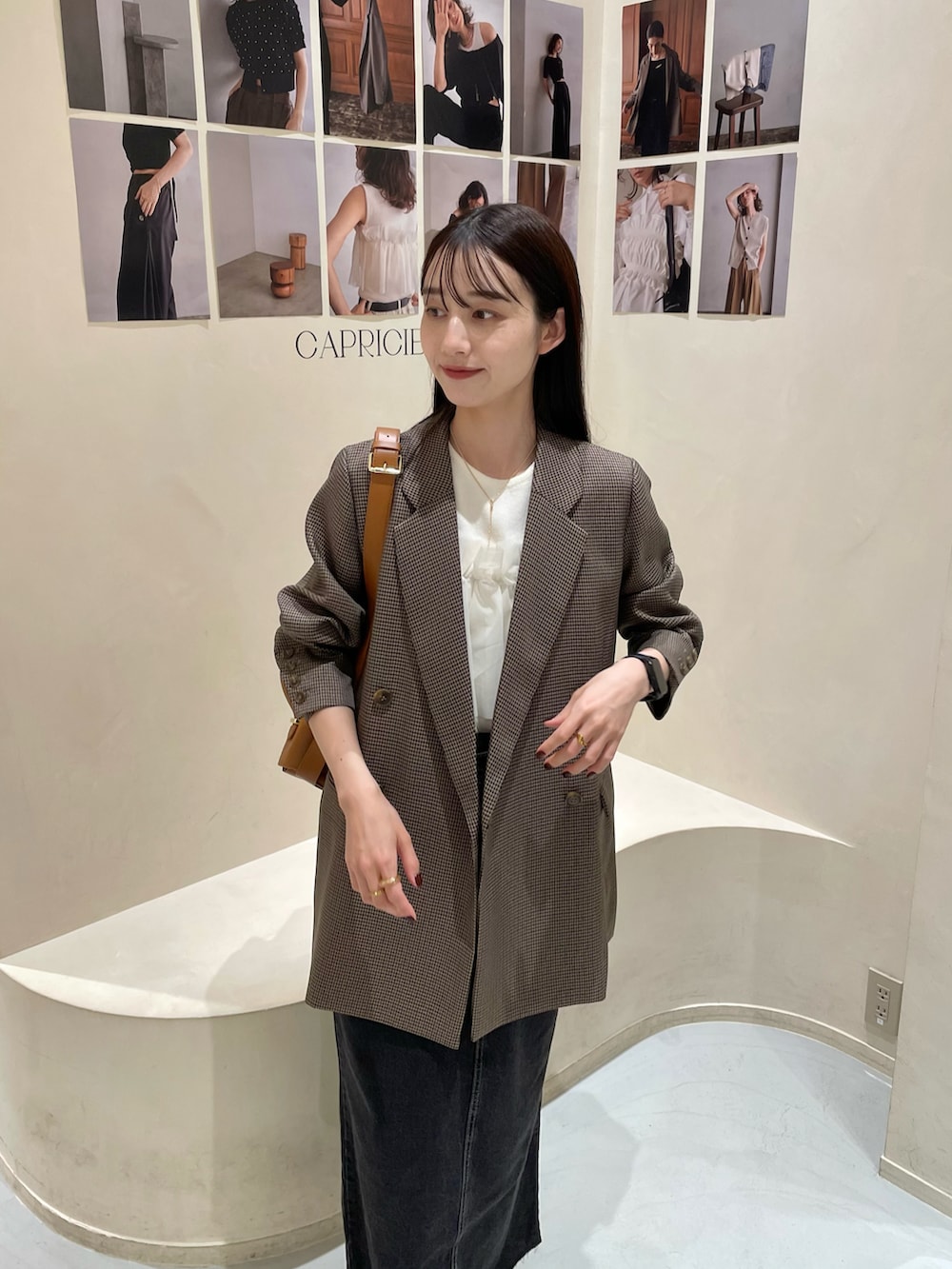 ブラウン系のテーラードジャケット、ブラック系のデニムスカート、ホワイト系のニット/セーターを着用したレディースの秋コーディネートの3枚目の写真