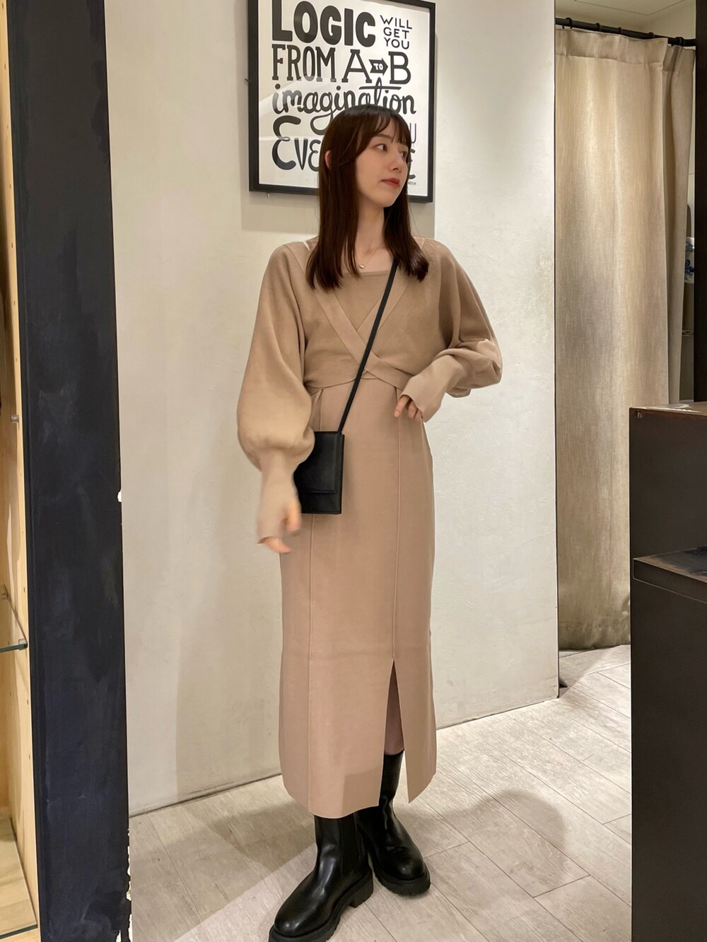 ベージュ系のワンピース、ブラック系のショルダーバッグ、ブラック系のブーツを着用したレディースの秋コーディネートの2枚目の写真