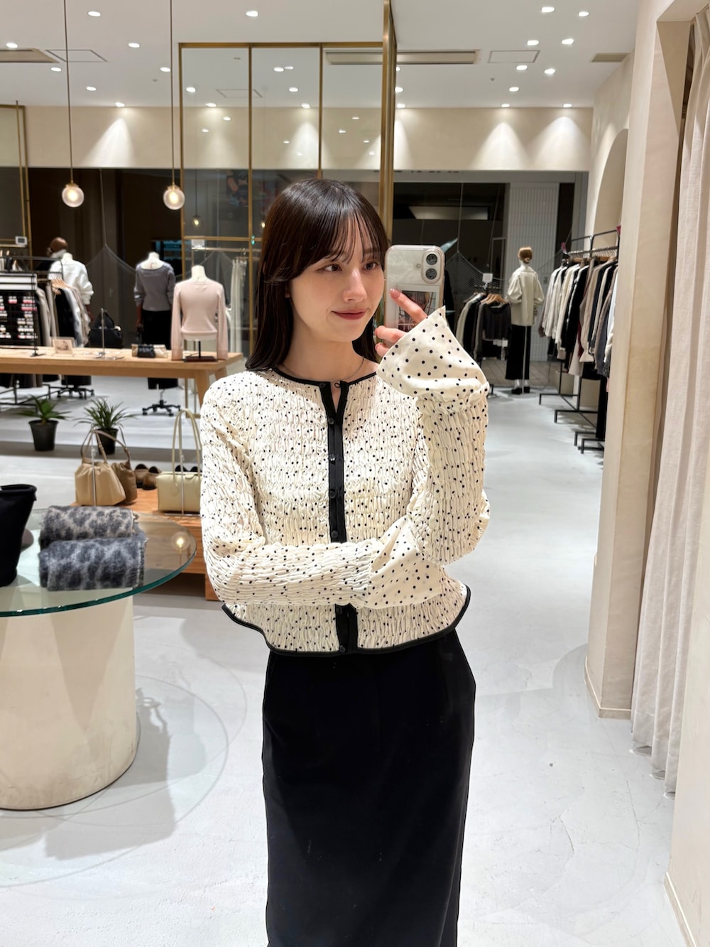 ホワイト系のショルダーバッグ、ホワイト系のシャツ/ブラウス、ブラック系のスカートを着用したレディースの春コーディネートの2枚目の写真