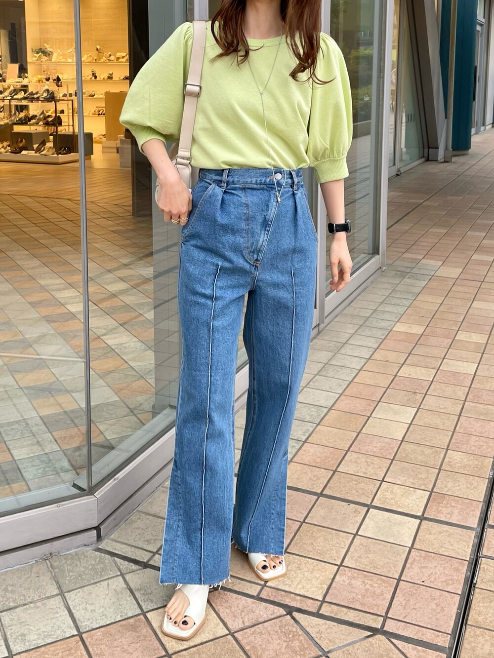 ブルー系のデニムパンツ、グリーン系のニット/セーター、ホワイト系のサンダルを着用したレディースの春コーディネートの2枚目の写真