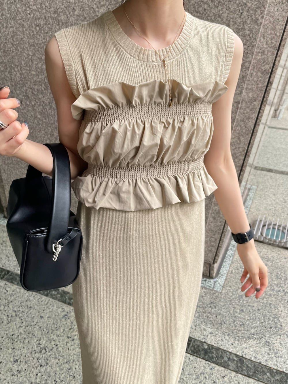 ブラック系のパンプス、ベージュ系のワンピース、ブラック系のショルダーバッグを着用したレディースの夏コーディネートの3枚目の写真