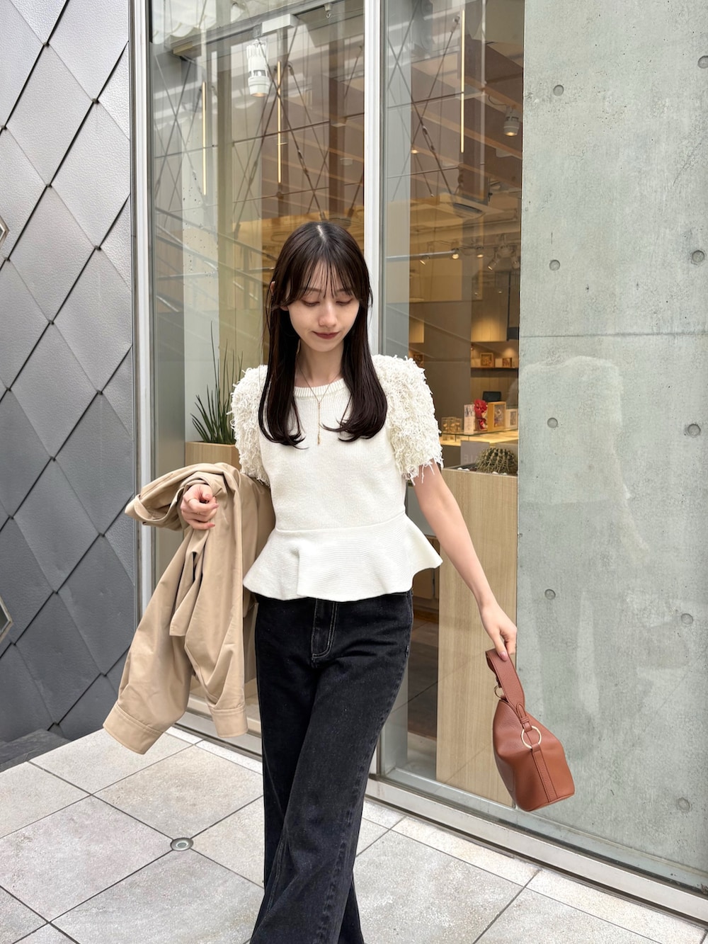 ブラック系のデニムパンツ、ホワイト系のニット/セーター、ベージュ系のトレンチコートを着用したレディースの春コーディネートの4枚目の写真