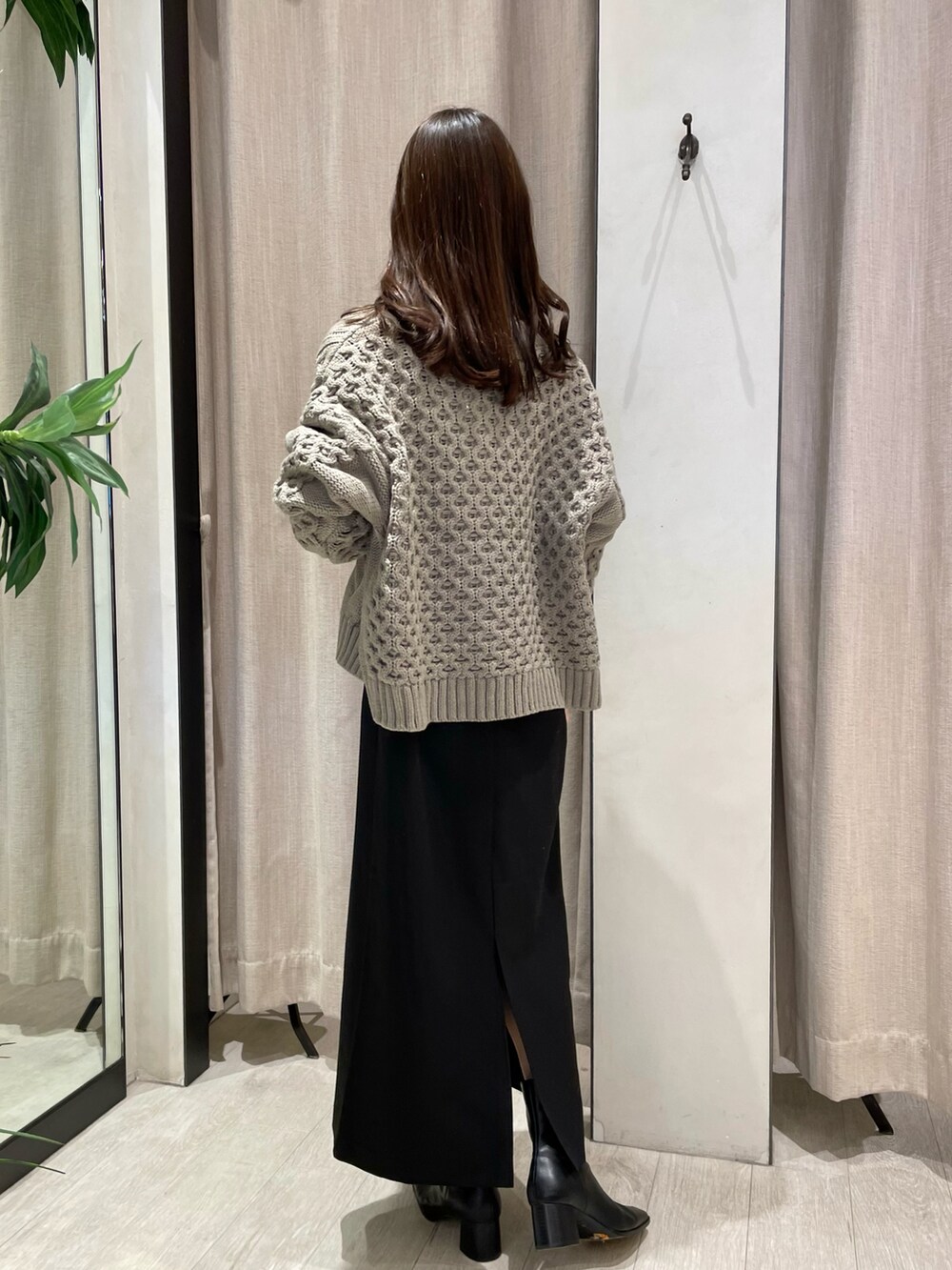 ベージュ系のカーディガン/ボレロ、ブラック系のワンピース、ブラック系のブーツを着用したレディースの冬コーディネートの2枚目の写真