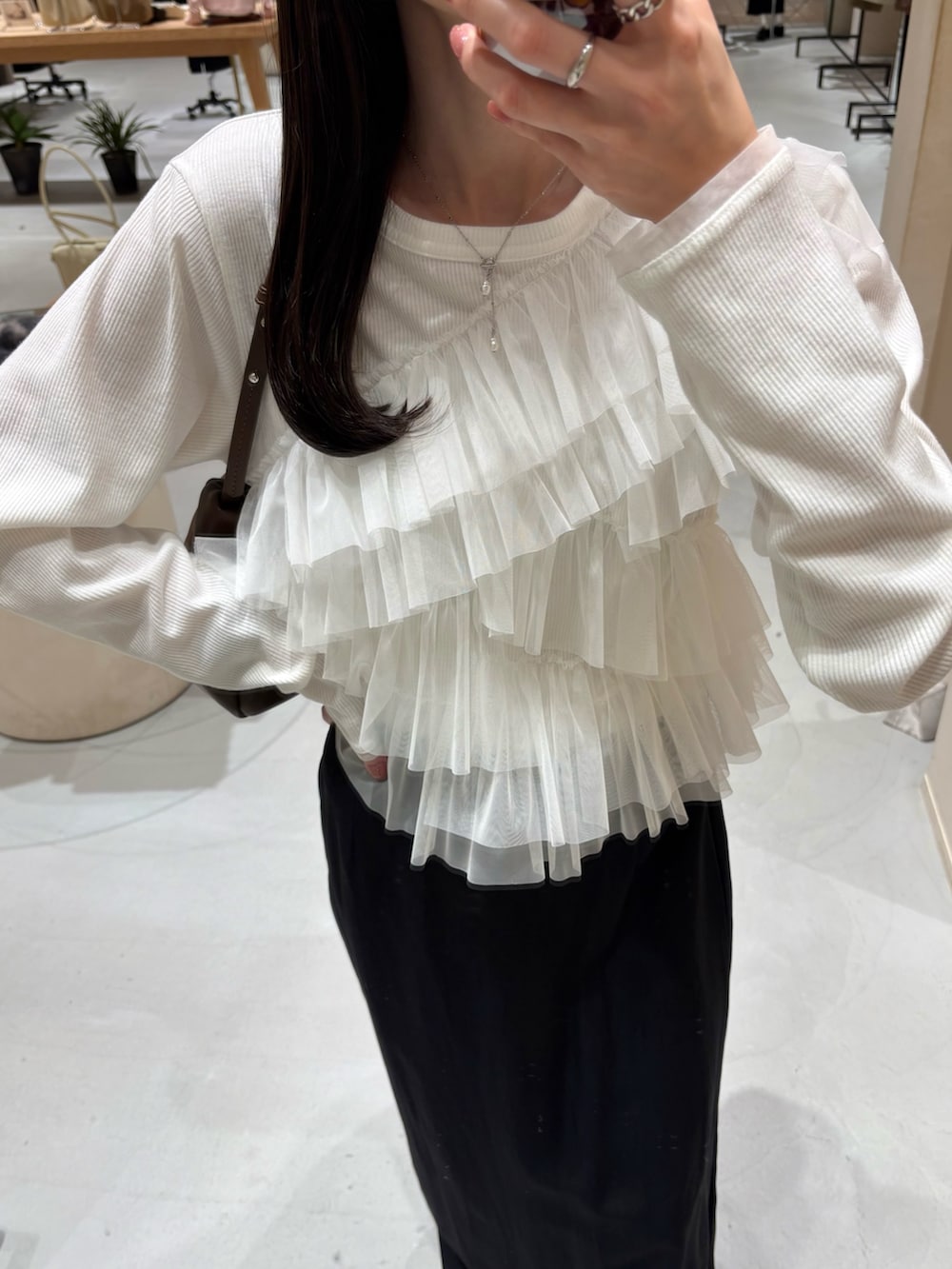 ブラック系のスカート、ホワイト系のTシャツ/カットソー、ブラウン系のショルダーバッグを着用したレディースの春コーディネートの3枚目の写真