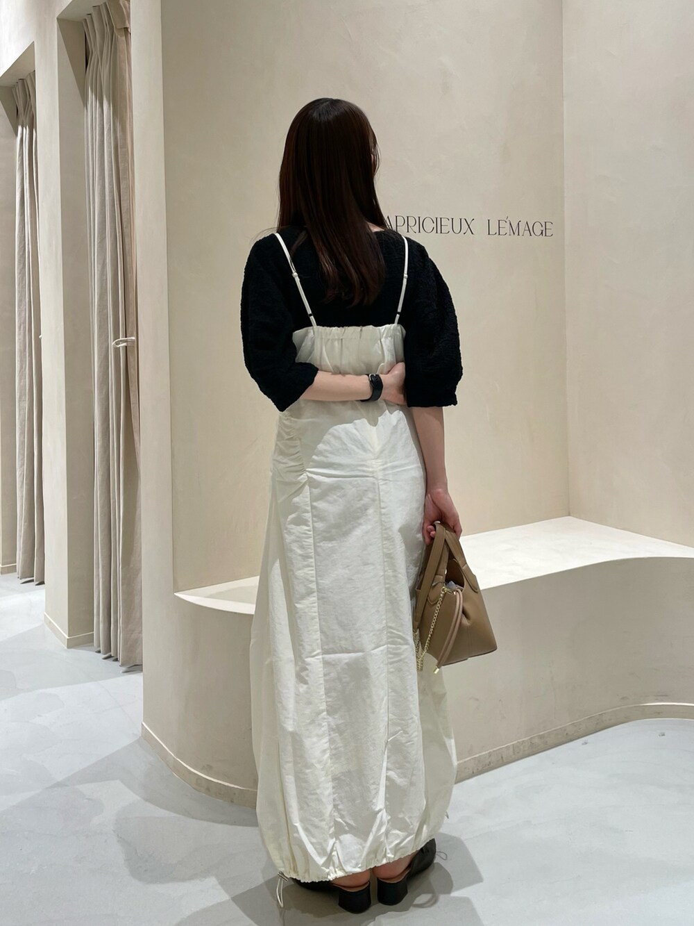 ホワイト系のワンピース、ブラック系のTシャツ/カットソー、ブラウン系のトートバッグを着用したレディースの春コーディネートの3枚目の写真