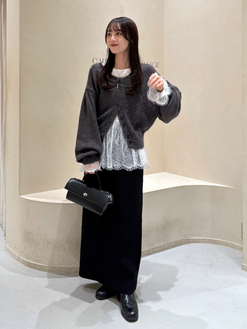 ブラック系のスカート、ブラック系のブーツ、ホワイト系のTシャツ/カットソーを着用したレディースの冬コーディネートの3枚目の写真