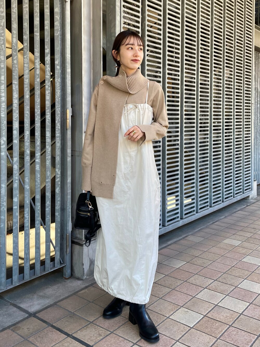 ホワイト系のワンピース、ベージュ系のニット/セーター、ブラック系のブーツを着用したレディースの冬コーディネートの2枚目の写真