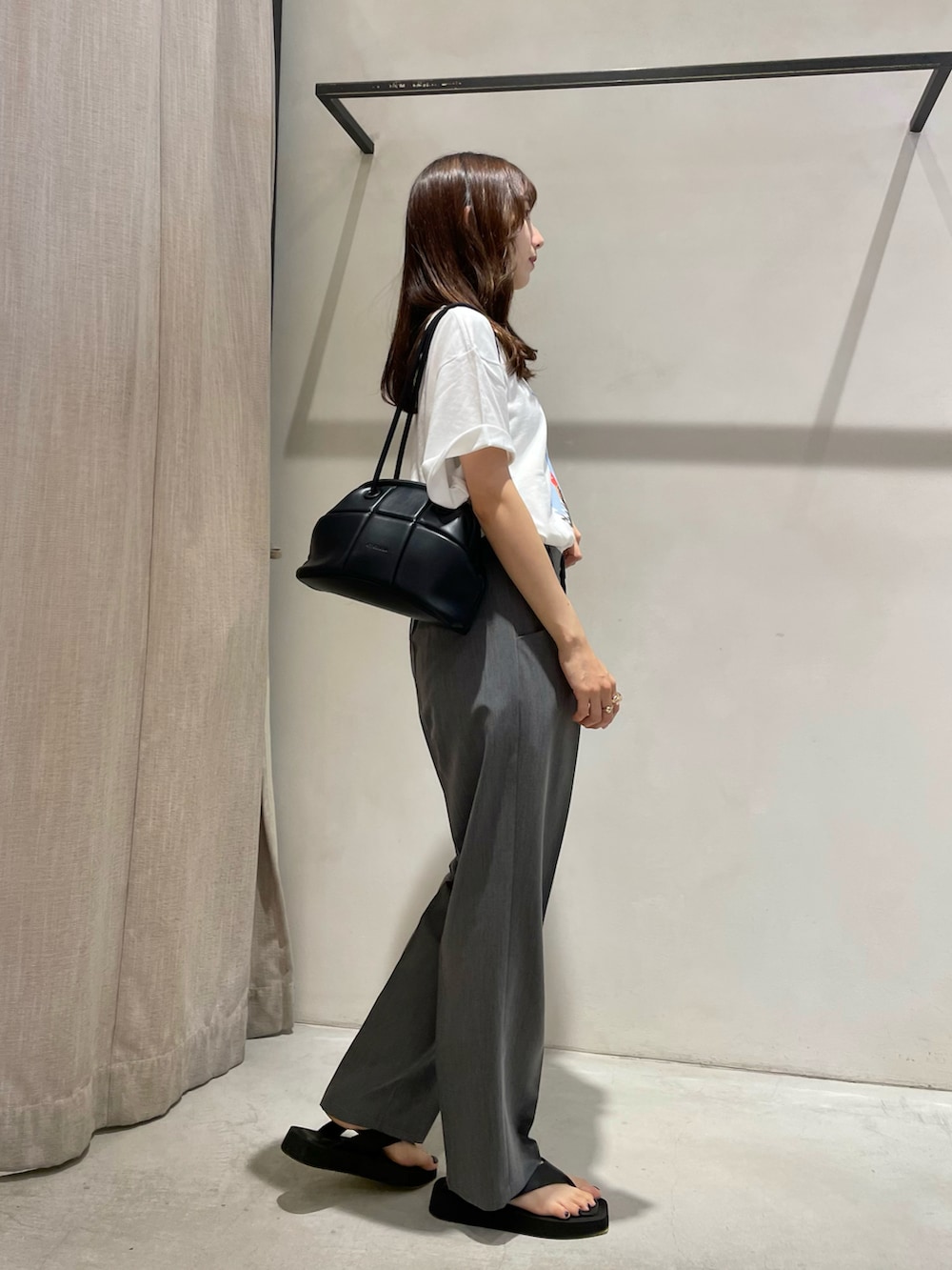 ホワイト系のTシャツ/カットソー、グレー系のスラックス、ブラック系のサンダルを着用したレディースの夏コーディネートの3枚目の写真