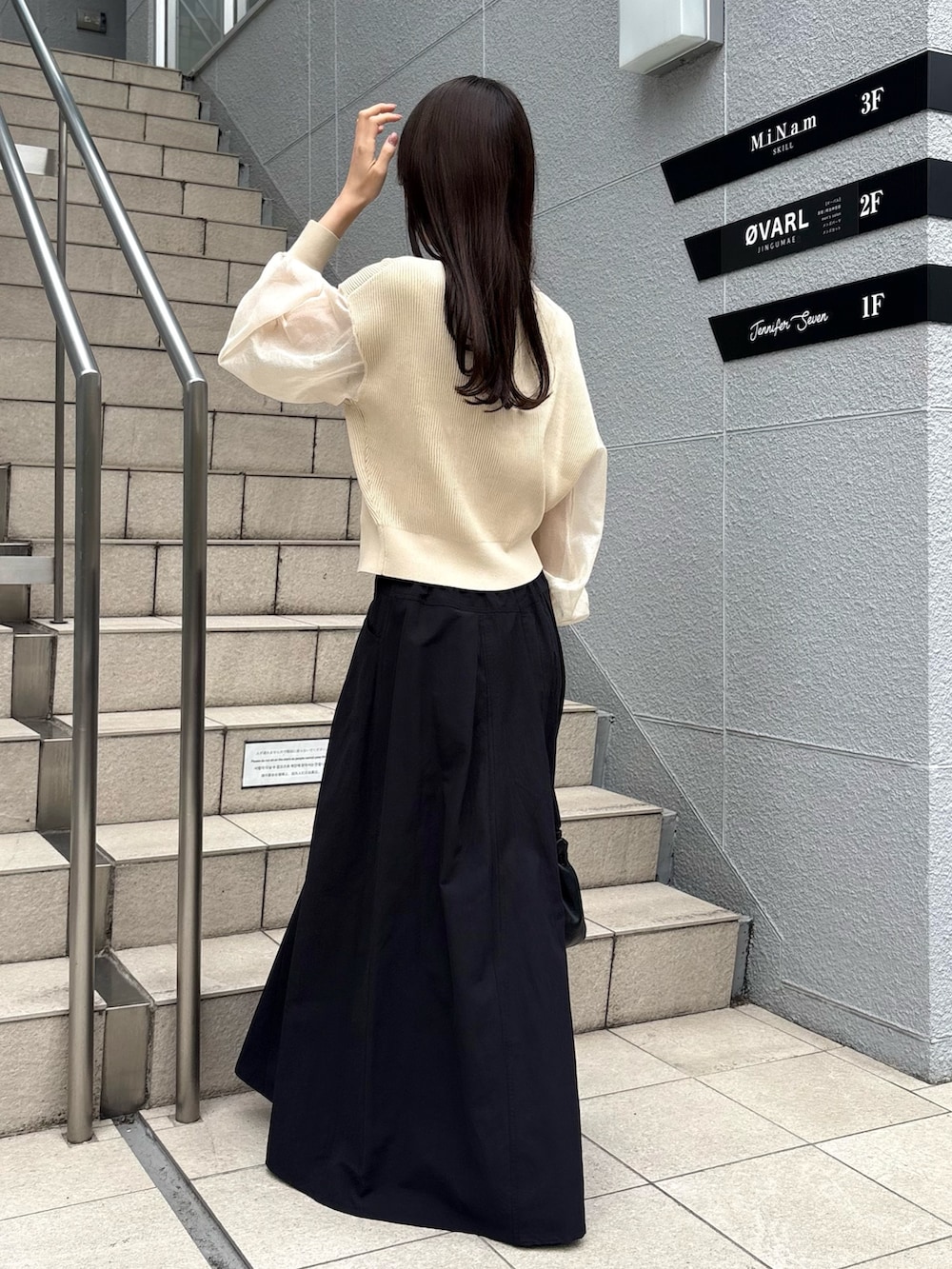 ブラック系のスカート、ベージュ系のカーディガン/ボレロ、ブラック系のパンプスを着用したレディースの春コーディネートの6枚目の写真