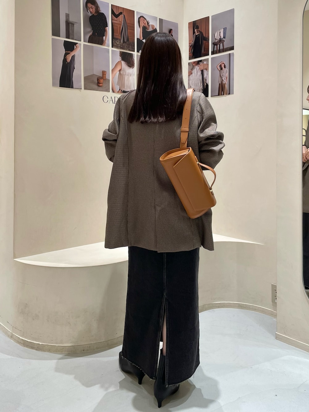 ブラウン系のテーラードジャケット、ブラック系のデニムスカート、ホワイト系のニット/セーターを着用したレディースの秋コーディネートの5枚目の写真