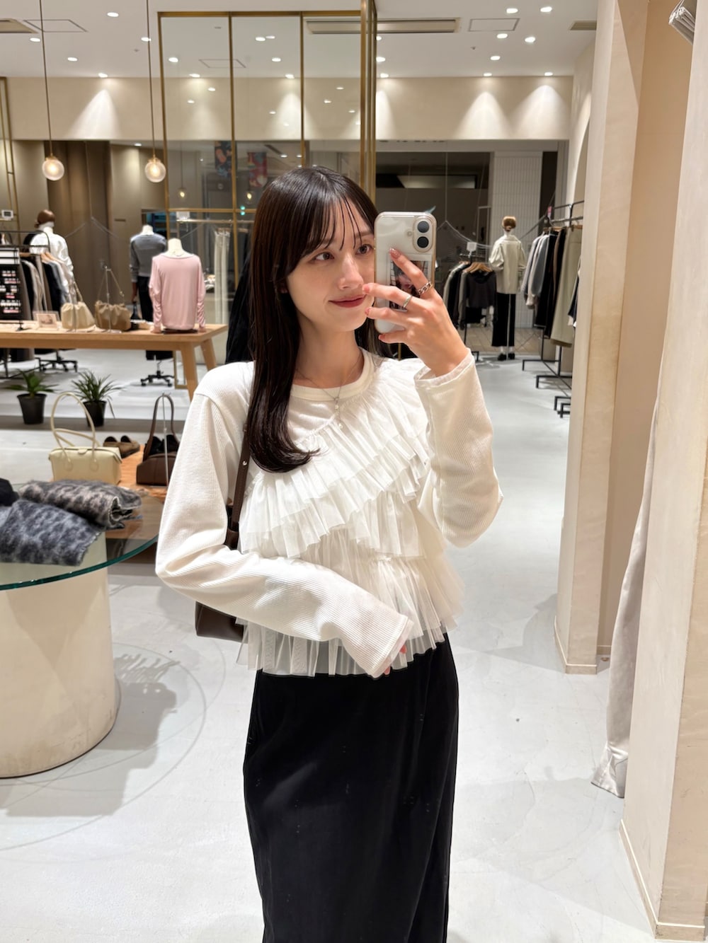 ブラック系のスカート、ホワイト系のTシャツ/カットソー、ブラウン系のショルダーバッグを着用したレディースの春コーディネートの2枚目の写真