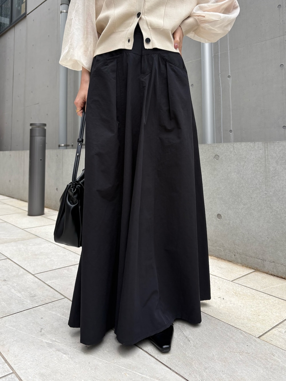 ブラック系のスカート、ベージュ系のカーディガン/ボレロ、ブラック系のパンプスを着用したレディースの春コーディネートの5枚目の写真