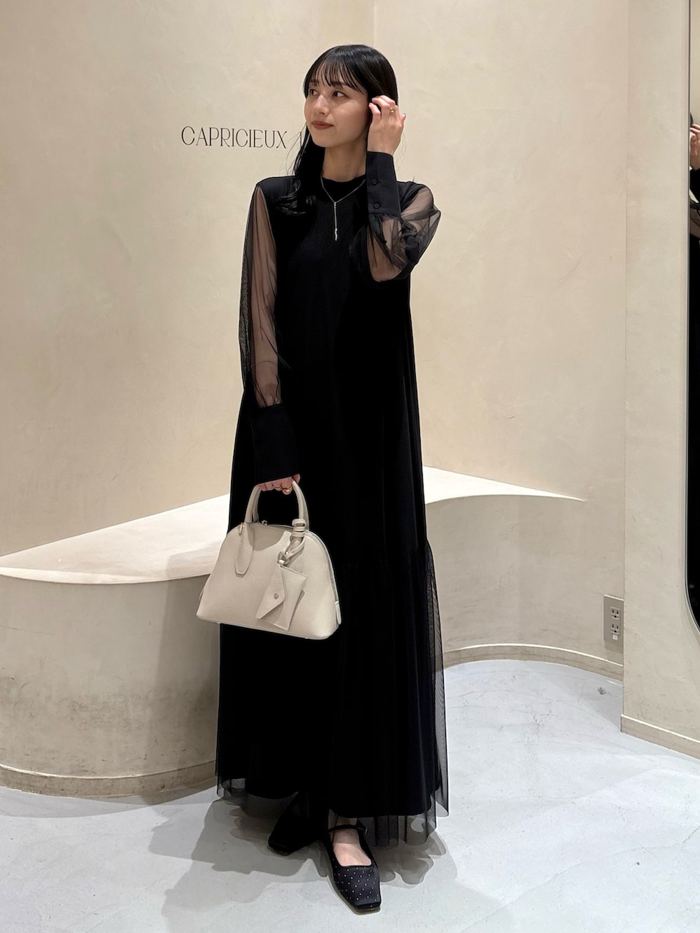 ブラック系のワンピース、ホワイト系のショルダーバッグ、ブラック系のパンプスを着用したレディースの春コーディネートの3枚目の写真