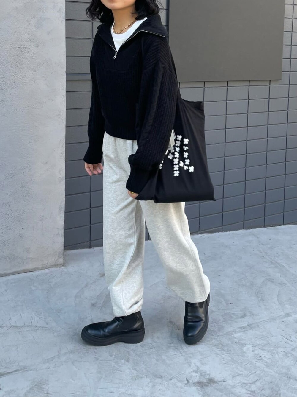 ブラック系のニット/セーター、グレー系のスウェットパンツを着用したレディースの冬コーディネートの2枚目の写真