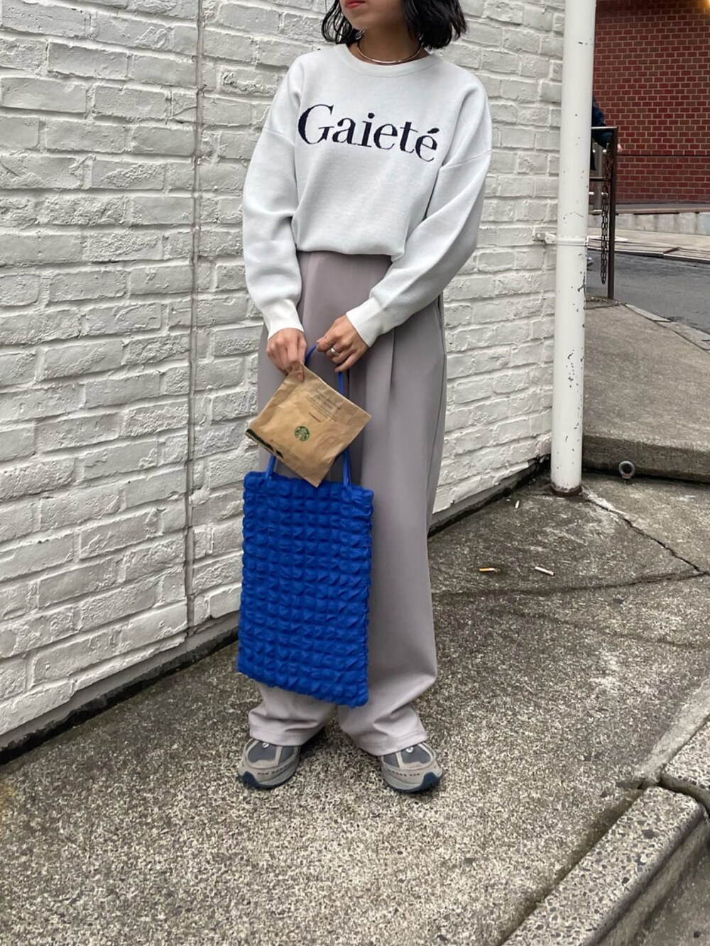 グレー系のその他パンツ、ホワイト系のニット/セーター、ブルー系のトートバッグを着用したレディースの冬コーディネートの2枚目の写真