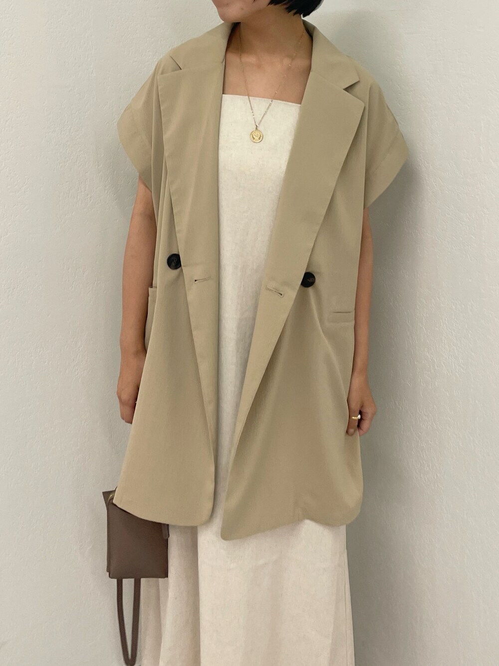 ベージュ系のベスト、ホワイト系のワンピース、ホワイト系のサンダルを着用したレディースの夏コーディネートの4枚目の写真