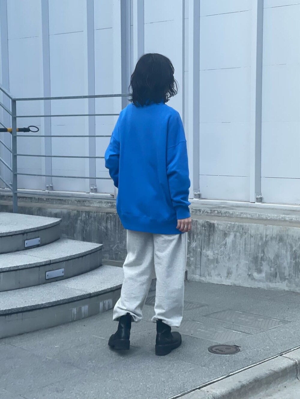 ブルー系のスウェット、グレー系のスウェットパンツ、ブラック系のブーツを着用したレディースの冬コーディネートの2枚目の写真