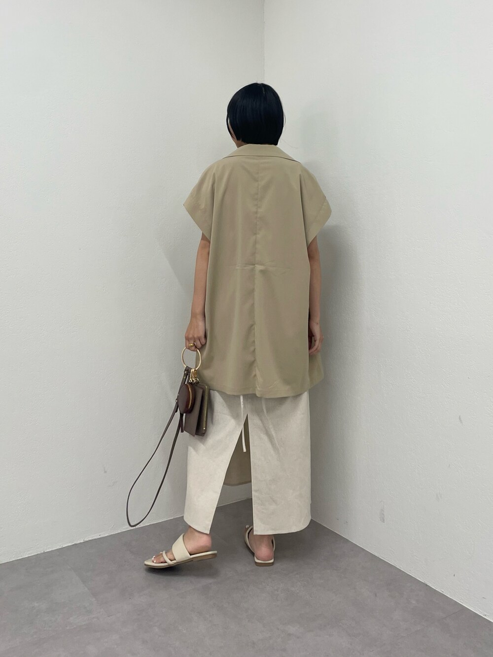 ベージュ系のベスト、ホワイト系のワンピース、ホワイト系のサンダルを着用したレディースの夏コーディネートの3枚目の写真