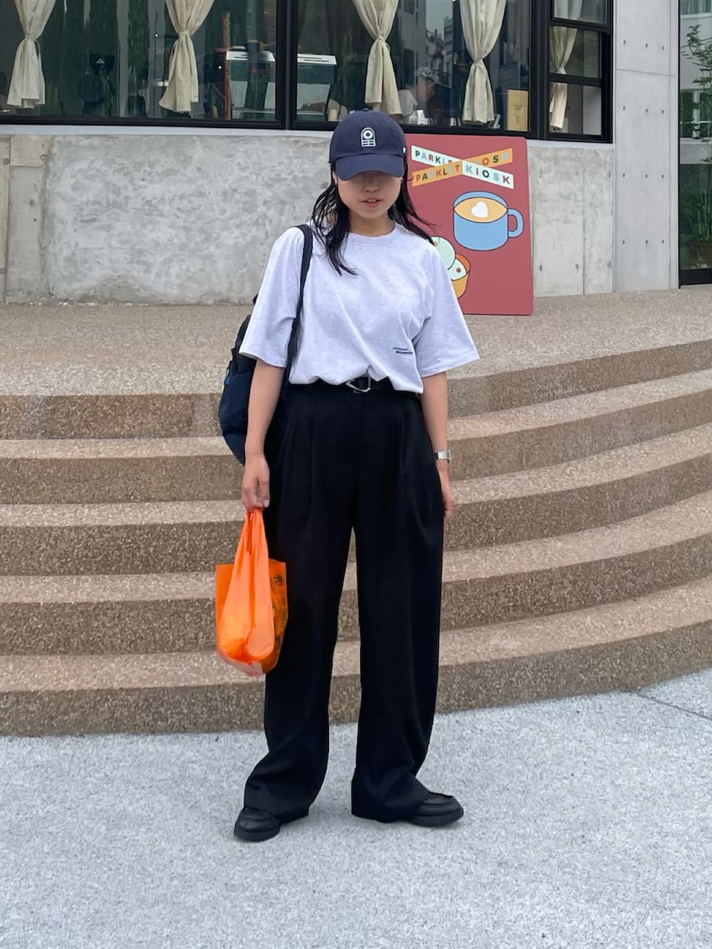 ブラック系のスラックス、ブルー系のTシャツ/カットソーを着用したレディースの春コーディネートの2枚目の写真