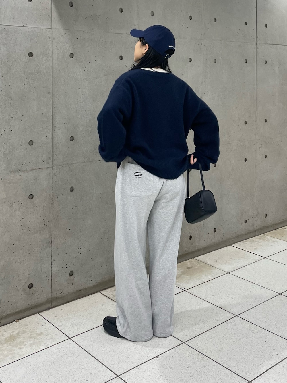 ブルー系のニット/セーター、ブラック系のハンドバッグ、グレー系のスウェットパンツを着用したレディースの冬コーディネートの2枚目の写真