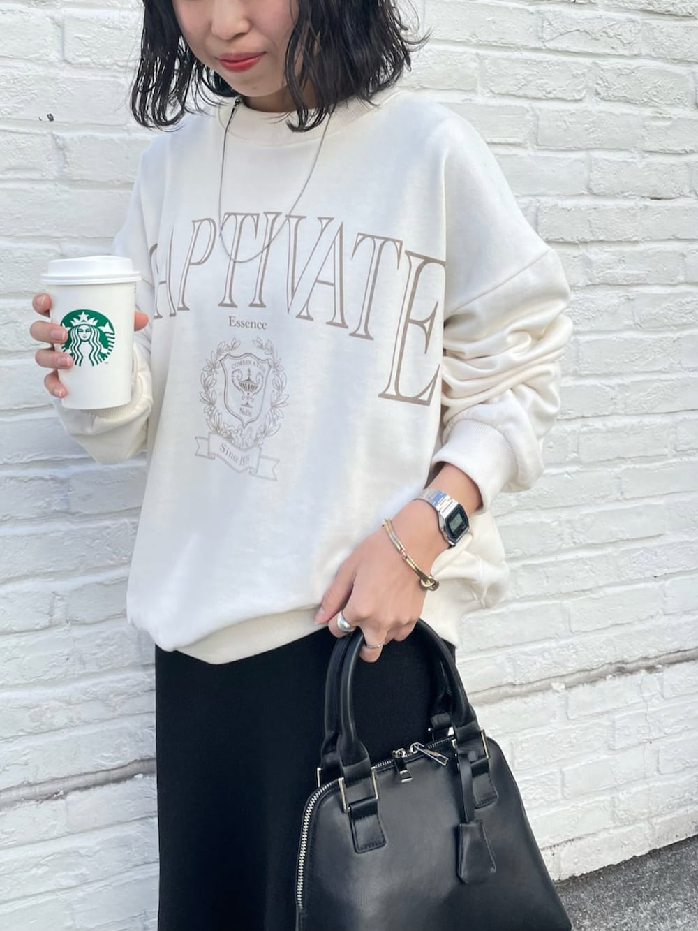 ブラック系のスカート、ホワイト系のスウェット、ブラック系のブーツを着用したレディースの冬コーディネートの4枚目の写真