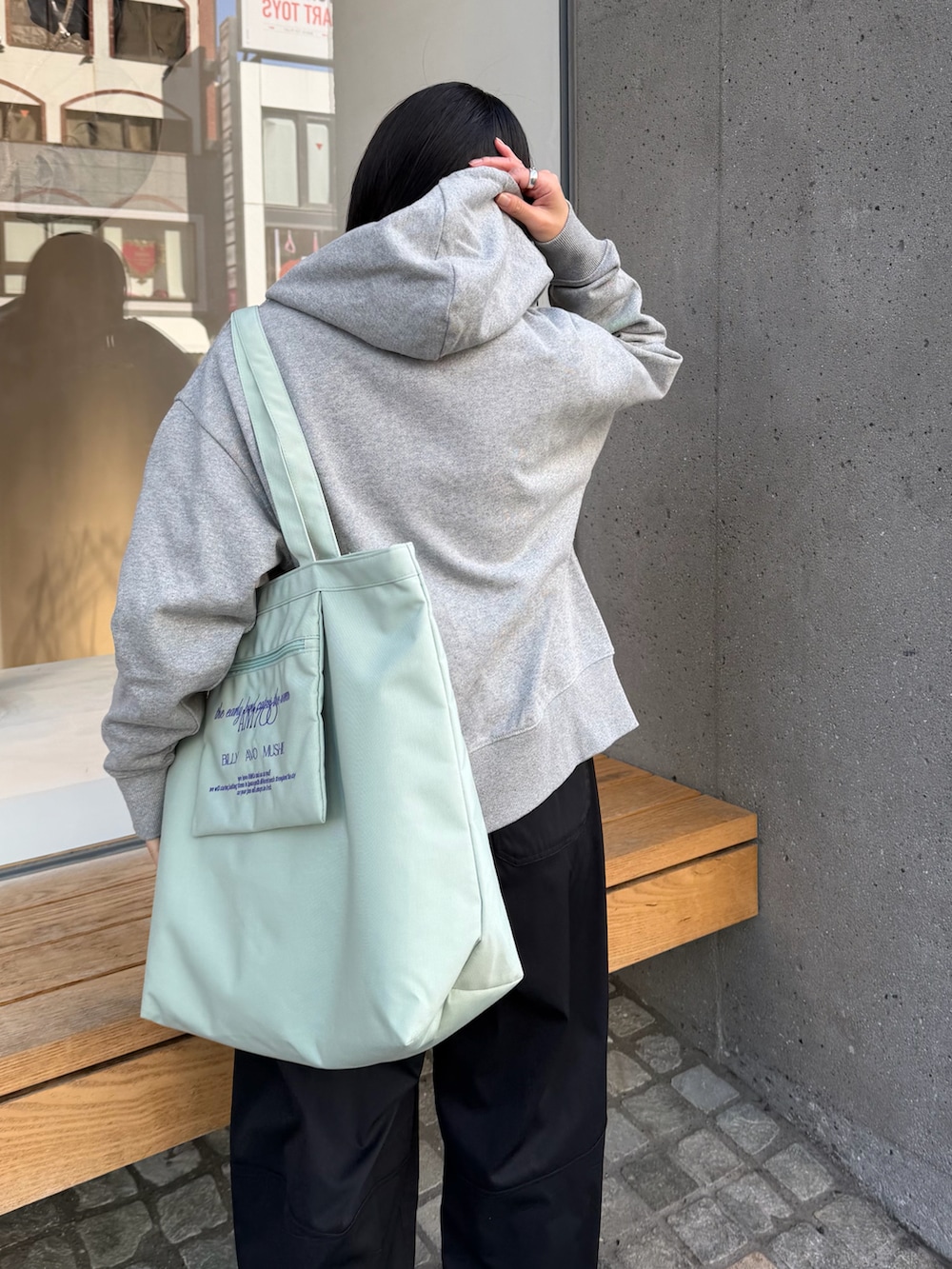 ブラック系のその他パンツ、グレー系のパーカー、ブルー系のトートバッグを着用したレディースの冬コーディネートの2枚目の写真