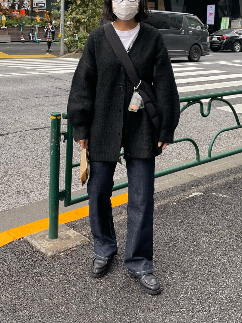 ブルー系のデニムパンツ、ブラック系のカーディガン/ボレロ、ブラック系のショルダーバッグを着用したレディースの秋コーディネートの4枚目の写真