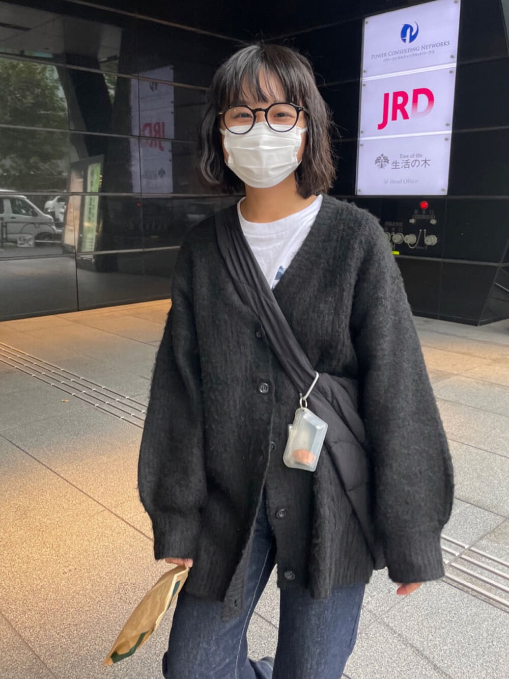 ブルー系のデニムパンツ、ブラック系のカーディガン/ボレロ、ブラック系のショルダーバッグを着用したレディースの秋コーディネートの3枚目の写真