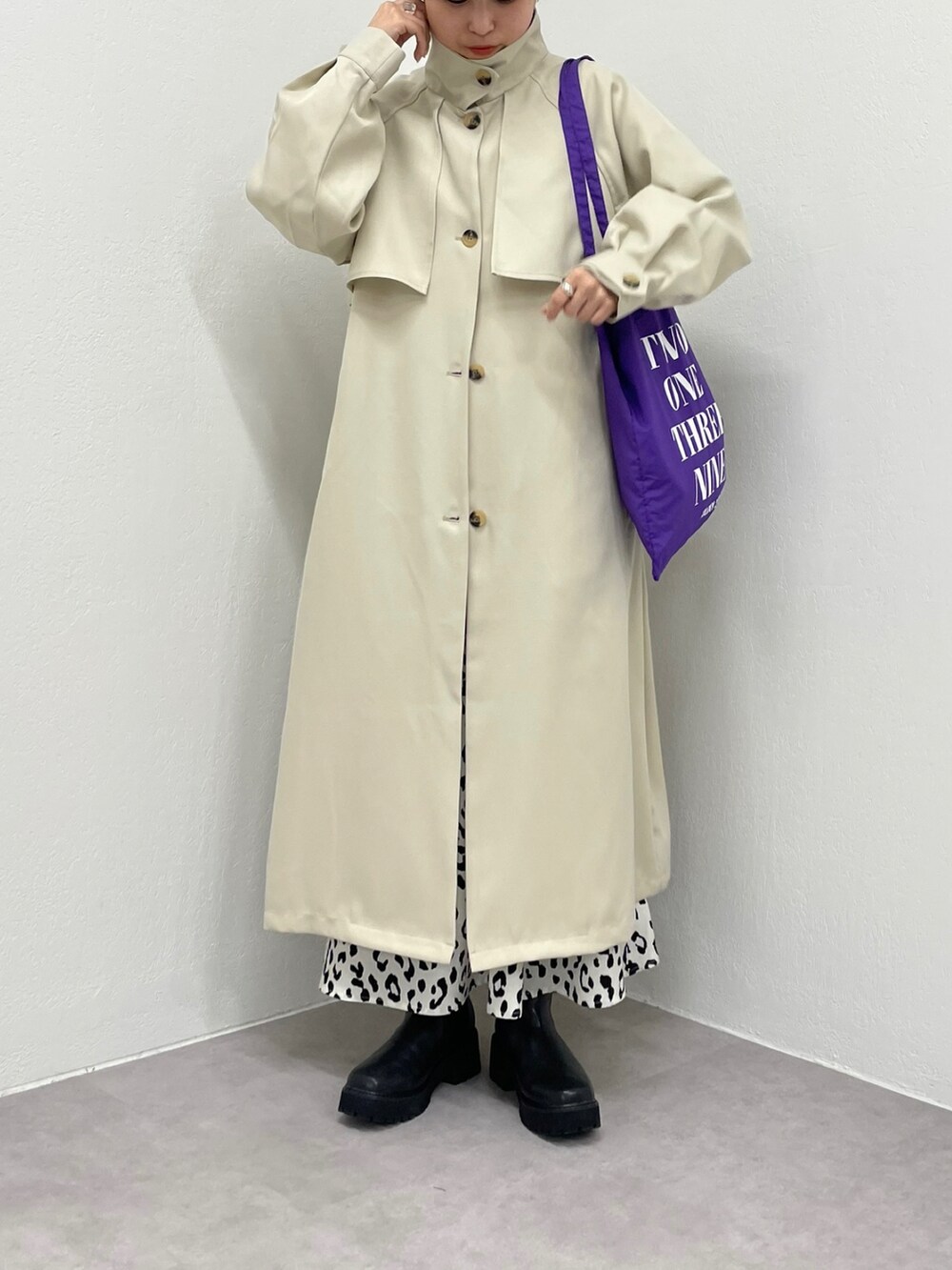パープル系のトートバッグ、ホワイト系のトレンチコート、ブラック系のブーツを着用したレディースの冬コーディネートの2枚目の写真