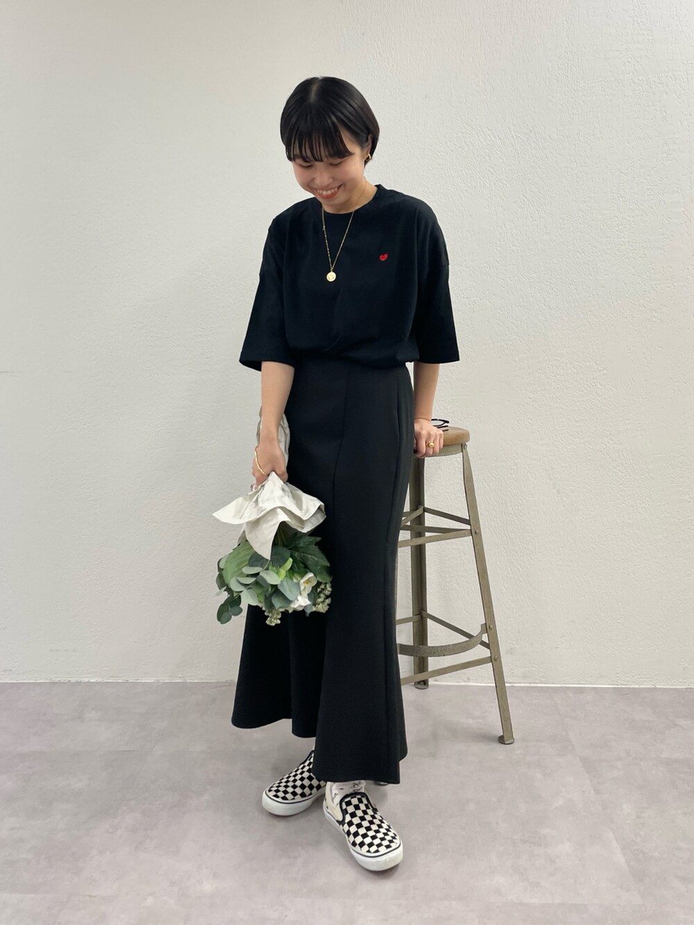 ホワイト系のスリッポン、ブラック系のスカート、ゴールド系のネックレスを着用したレディースの春コーディネートの2枚目の写真