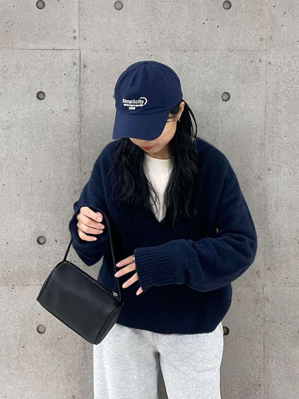 ブルー系のニット/セーター、ブラック系のハンドバッグ、グレー系のスウェットパンツを着用したレディースの冬コーディネートの3枚目の写真