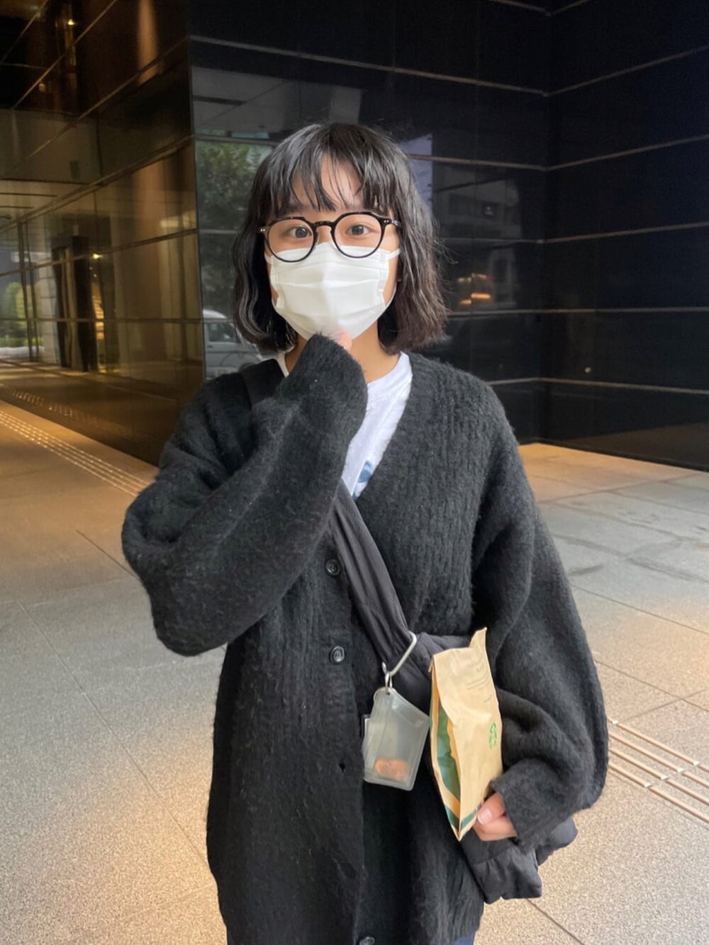 ブルー系のデニムパンツ、ブラック系のカーディガン/ボレロ、ブラック系のショルダーバッグを着用したレディースの秋コーディネートの2枚目の写真