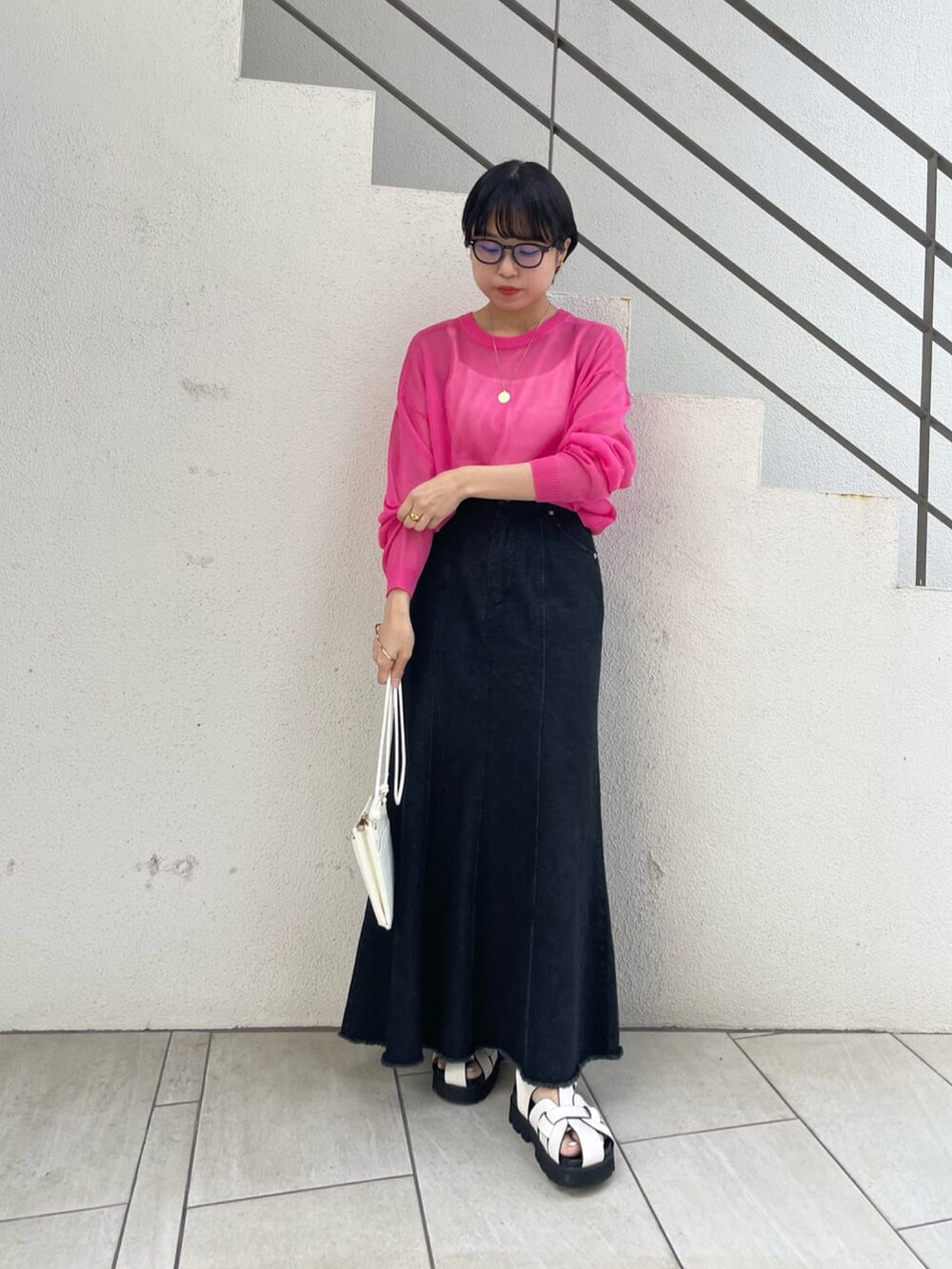 ホワイト系のサンダル、ブラック系のデニムスカート、ブラック系のショルダーバッグを着用したレディースの春コーディネートの3枚目の写真