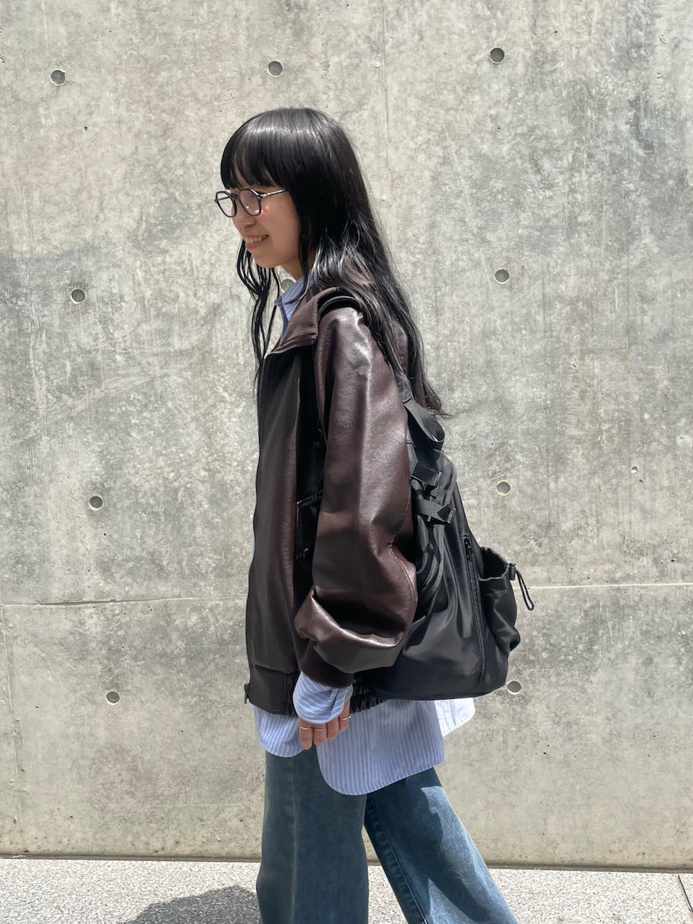 ブラウン系のライダースジャケット、ブルー系のシャツ/ブラウス、ブルー系のデニムパンツを着用したレディースの夏コーディネートの3枚目の写真