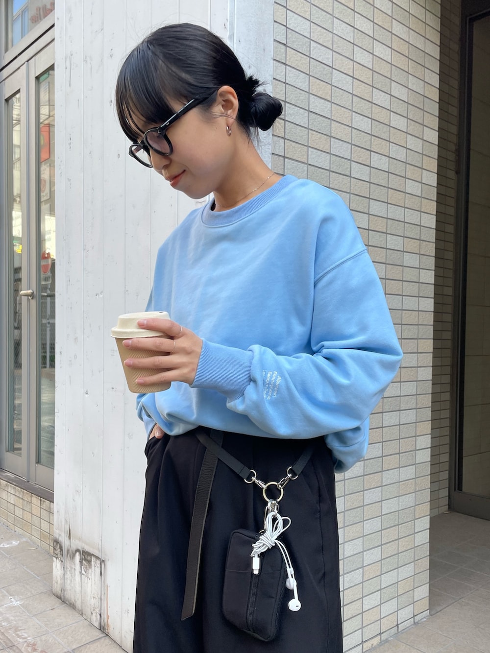 ブラック系のスラックス、ブラック系のショルダーバッグ、ブルー系のスウェットを着用したレディースの秋コーディネートの3枚目の写真