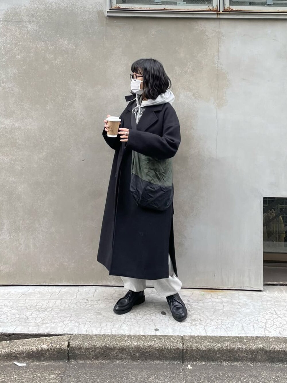 ブラック系のチェスターコート、グレー系のスウェットパンツ、グレー系のパーカーを着用したレディースの冬コーディネートの2枚目の写真