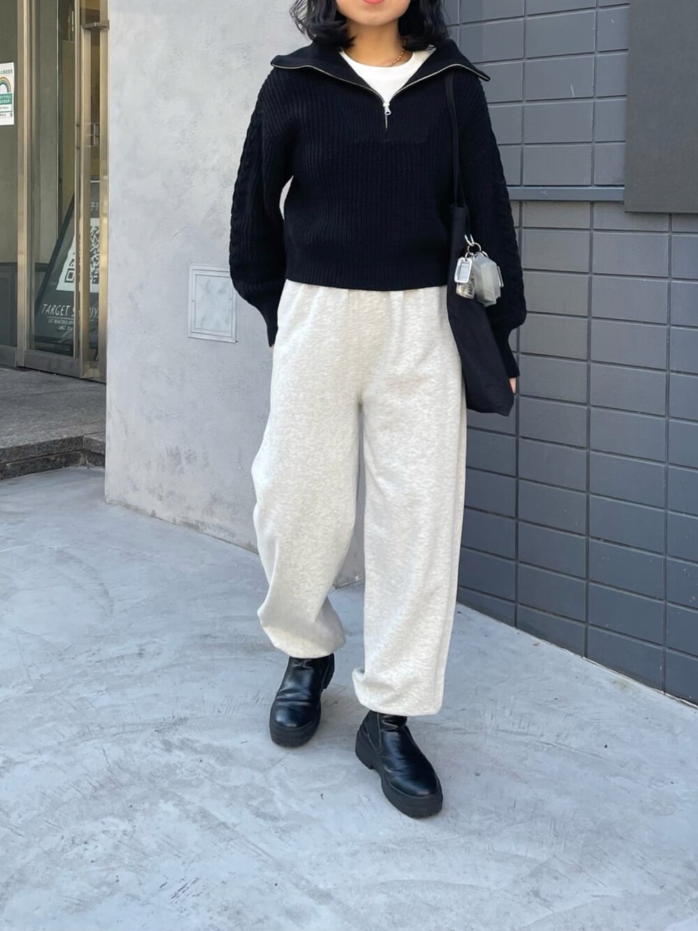 ブラック系のニット/セーター、グレー系のスウェットパンツを着用したレディースの冬コーディネートの3枚目の写真