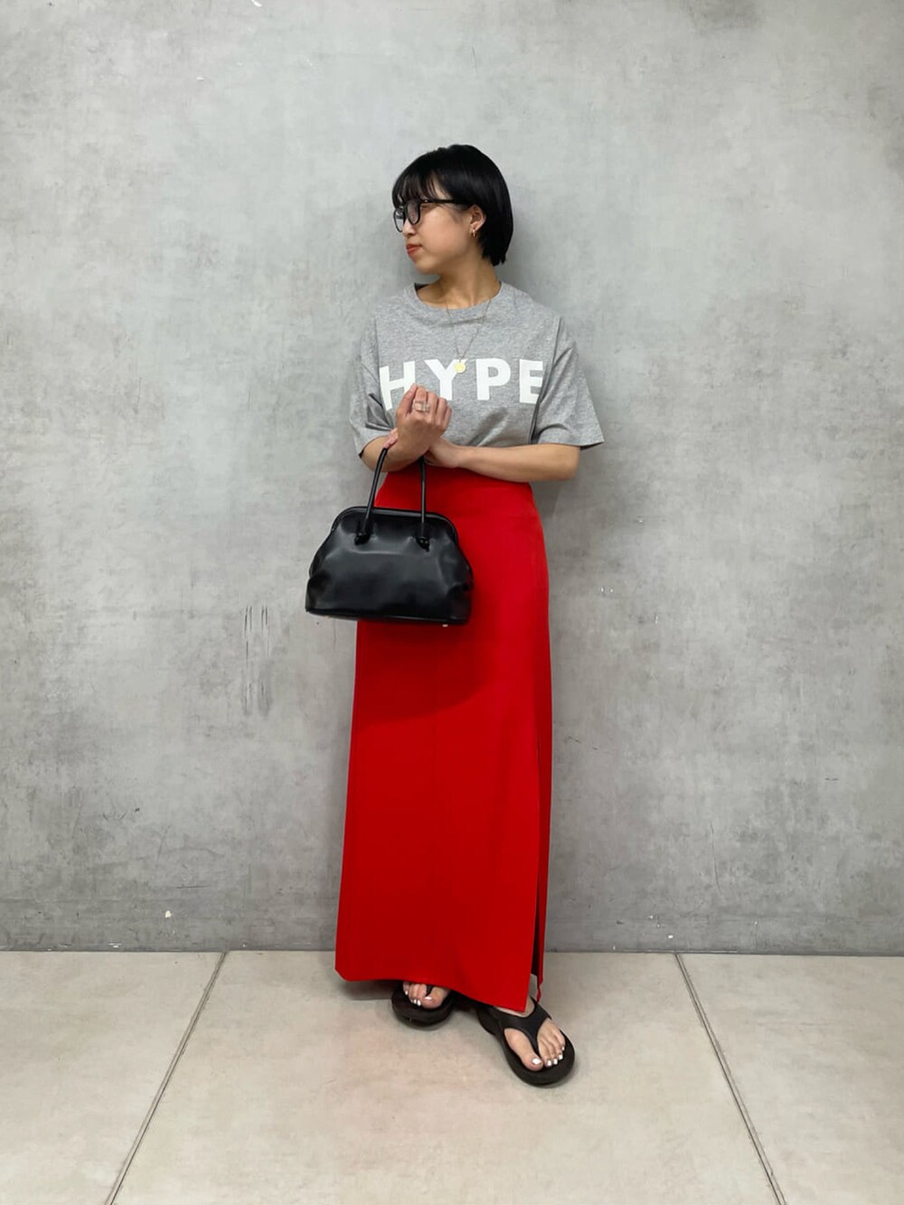 ブラック系のスカート、ホワイト系のTシャツ/カットソー、ブラック系のトートバッグを着用したレディースの夏コーディネートの2枚目の写真