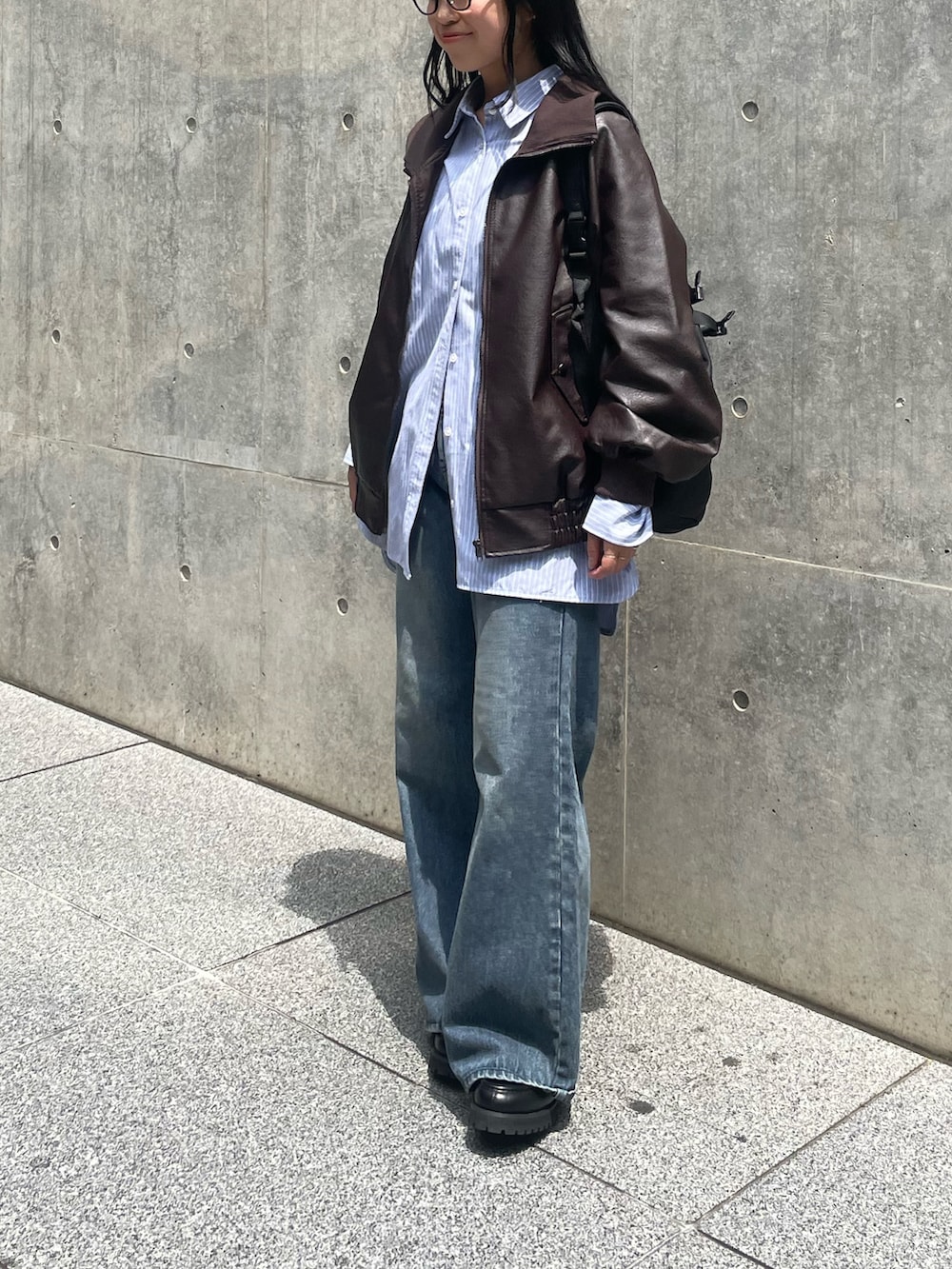 ブラウン系のライダースジャケット、ブルー系のシャツ/ブラウス、ブルー系のデニムパンツを着用したレディースの夏コーディネートの2枚目の写真