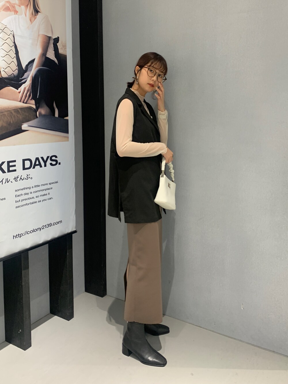 ホワイト系のハンドバッグ、ブラウン系のスカート、ブラック系のブーツを着用したレディースの秋コーディネートの3枚目の写真