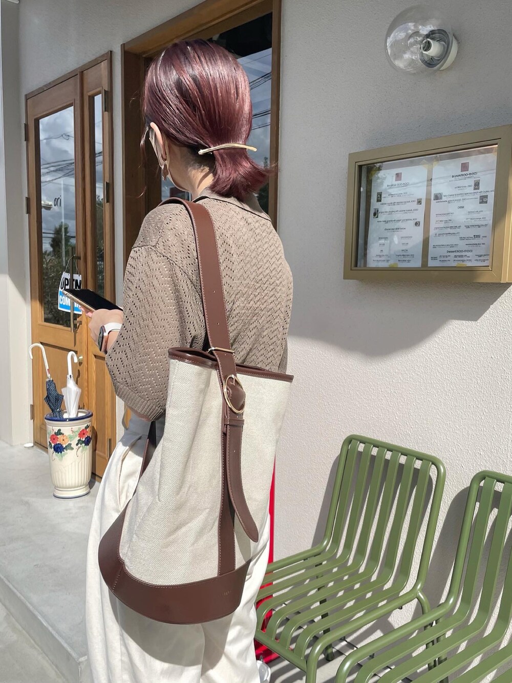 ブラック系のサンダル、ホワイト系のパンツ、ブラウン系のショルダーバッグを着用したレディースの秋コーディネートの2枚目の写真