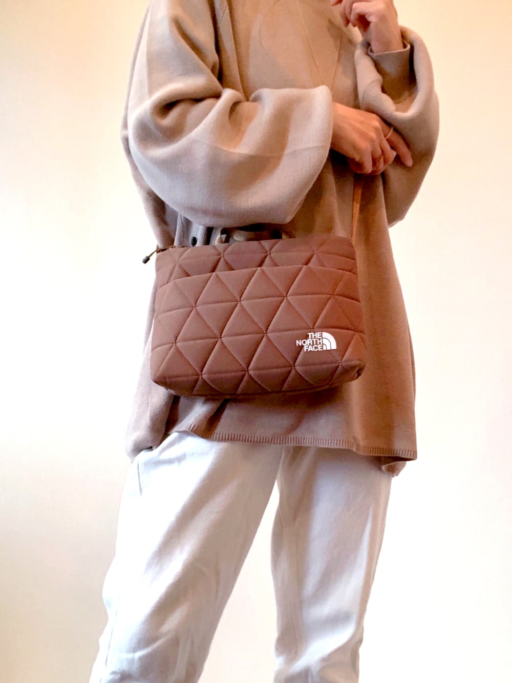 ブラウン系のショルダーバッグ、ホワイト系のデニムパンツ、ベージュ系のニット/セーターを着用したレディースの秋コーディネートの2枚目の写真