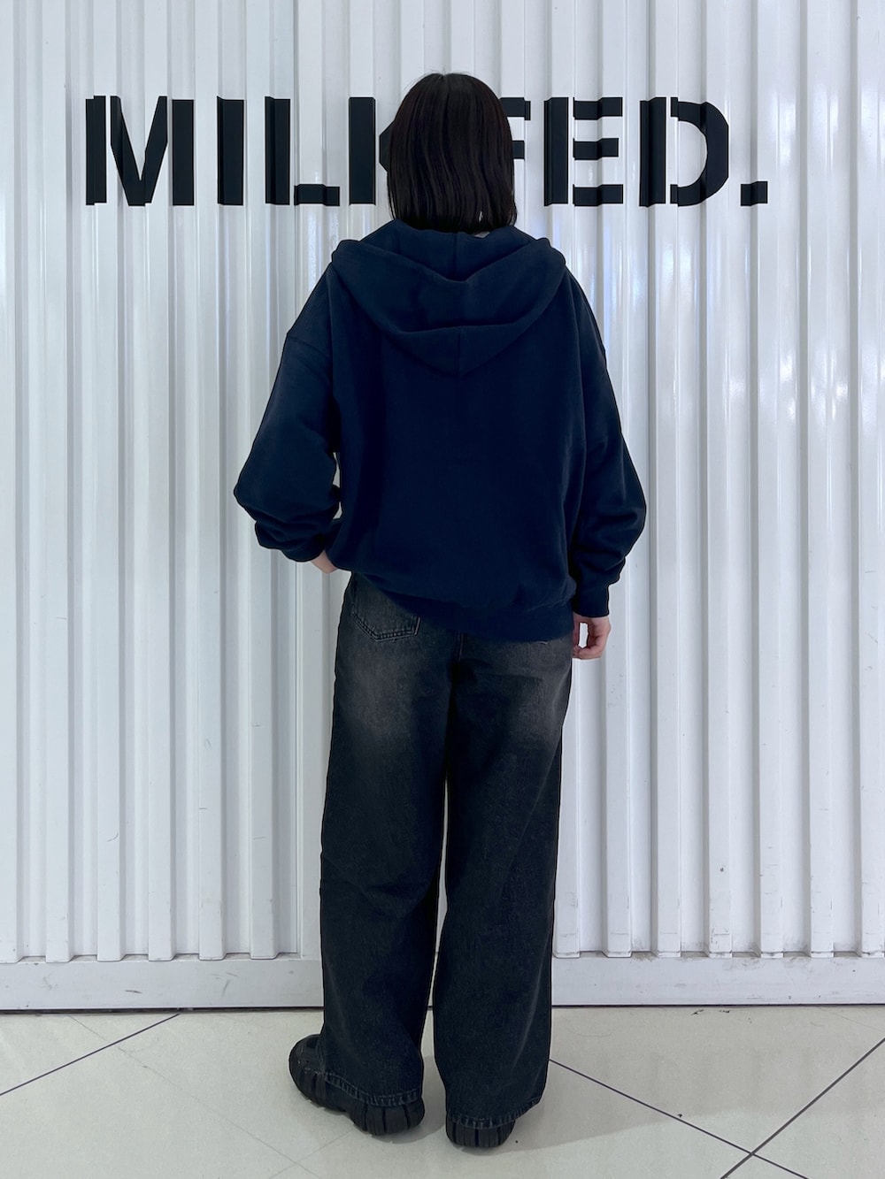 ブルー系のパーカー、ブラック系のデニムパンツ、ブラック系のお弁当箱を着用したレディースの秋コーディネートの4枚目の写真