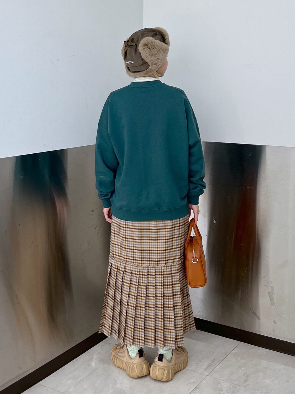 ベージュ系のスカート、グリーン系のスウェット、ブラウン系のボストンバッグを着用したレディースの冬コーディネートの2枚目の写真