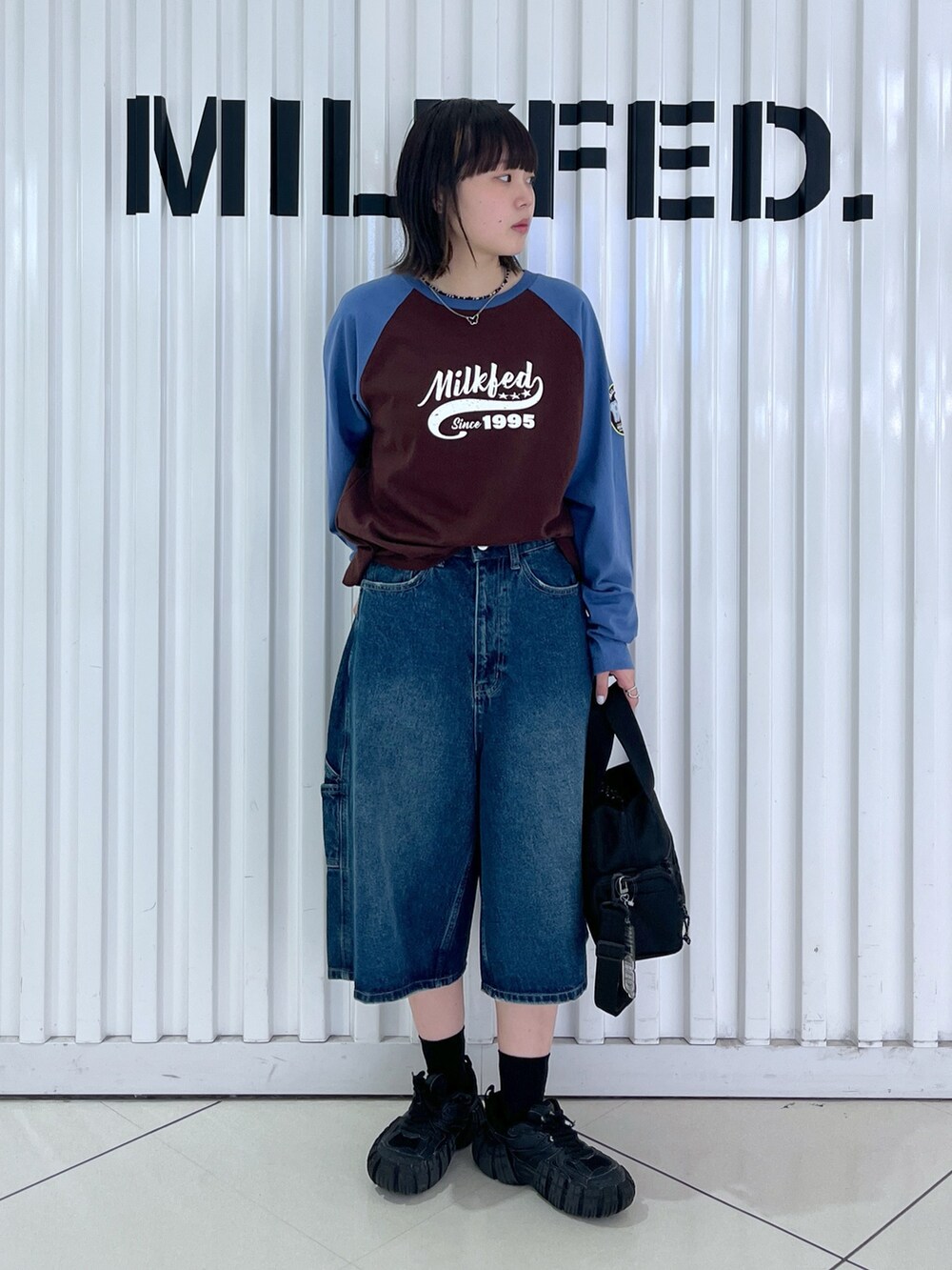 ブラウン系のTシャツ/カットソー、ブルー系のデニムパンツ、ブラック系のショルダーバッグを着用したレディースの秋コーディネートの3枚目の写真