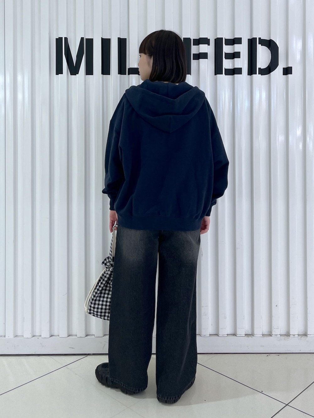 ブルー系のパーカー、ブラック系のデニムパンツ、ブラック系のお弁当箱を着用したレディースの秋コーディネートの2枚目の写真