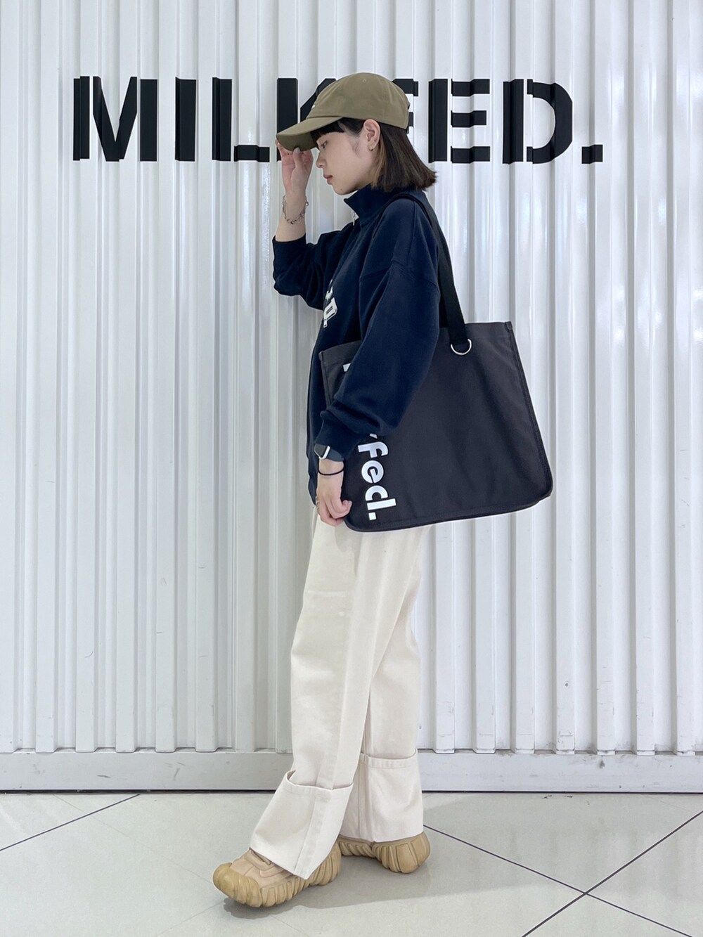 ブルー系のスウェット、グレー系のトートバッグ、ホワイト系のデニムパンツを着用したレディースの秋コーディネートの2枚目の写真