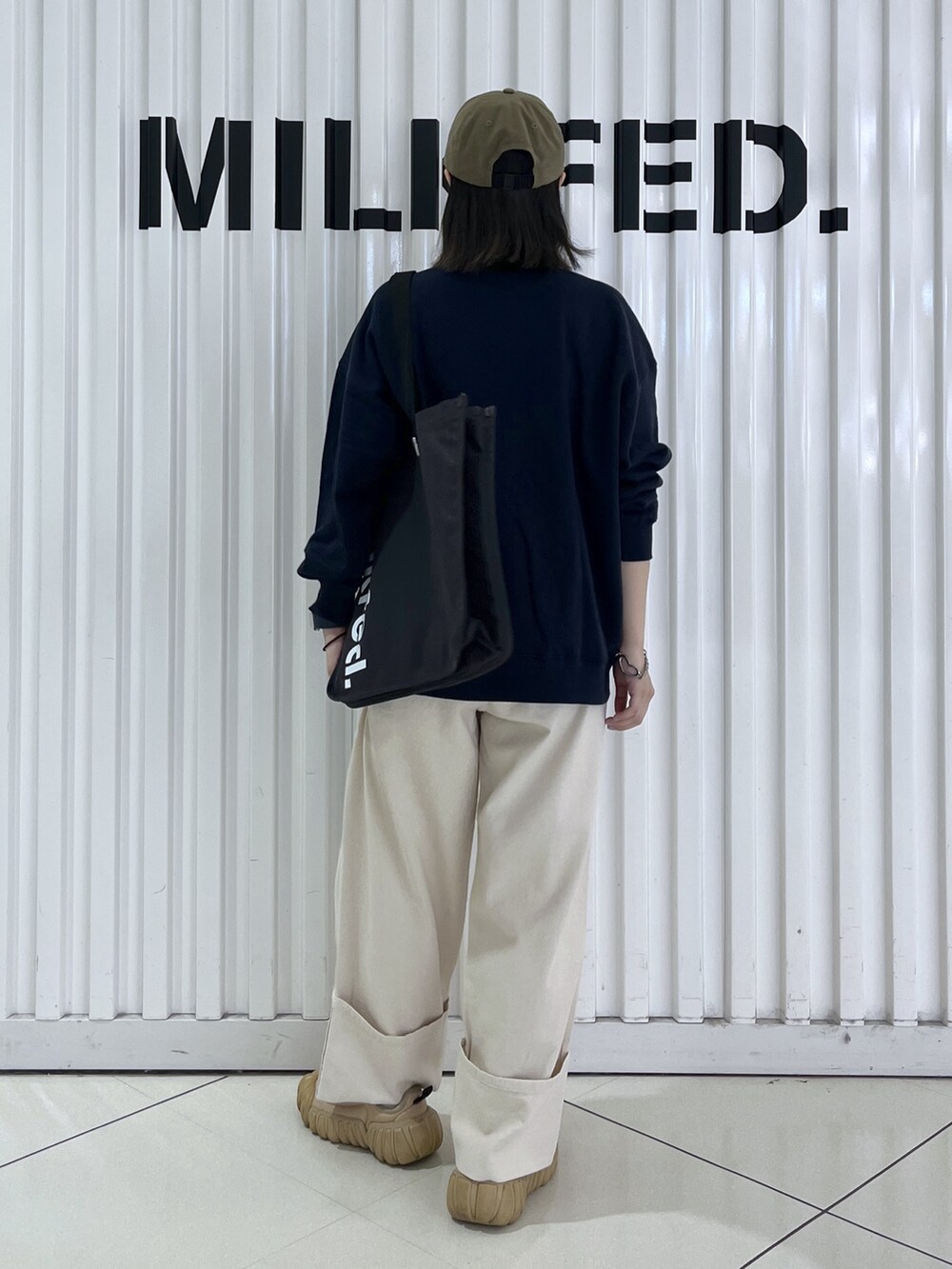 ブルー系のスウェット、グレー系のトートバッグ、ホワイト系のデニムパンツを着用したレディースの秋コーディネートの3枚目の写真